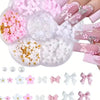 A clear plastic container holds various pink and white butterfly bow nail charms and glitter accents for manicures.