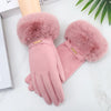 A pair of soft pink plush wrist gloves with fluffy faux fur cuffs resting on a white surface.