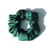A dark emerald green silk hair scrunchie tied in a gathered, ruched style.