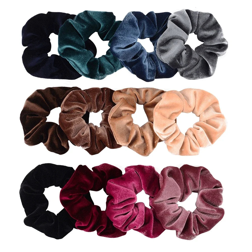 A set of six velvet scrunchies in various shades including dark green, navy blue, gray, brown, and pink.