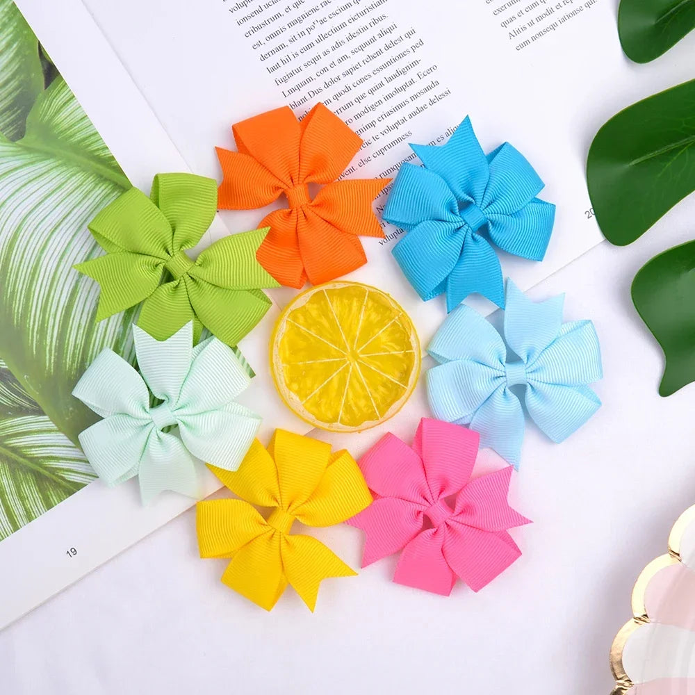 Assorted grosgrain ribbon hair bow clips in various colors including orange, yellow, green, and blue.