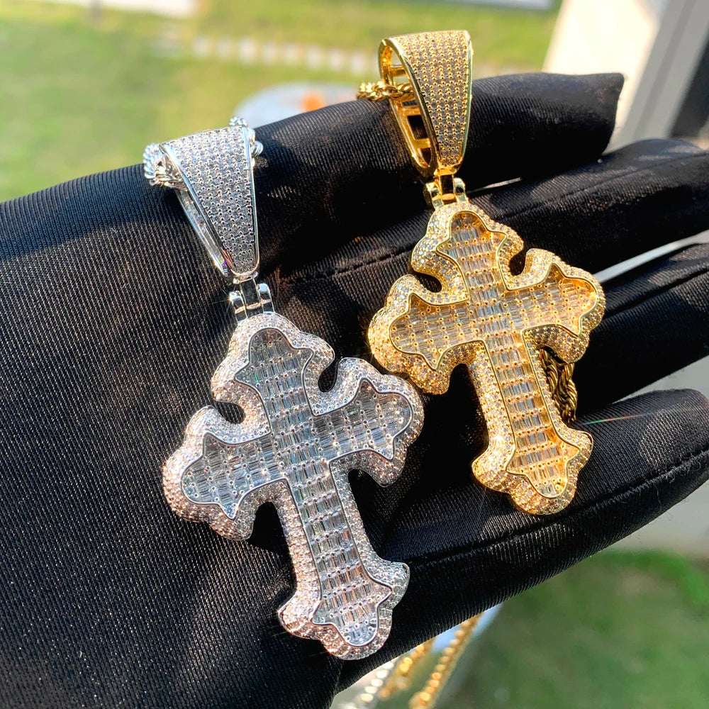 Une main tient un pendentif de croix argenté serti et un pendentif de croix doré.