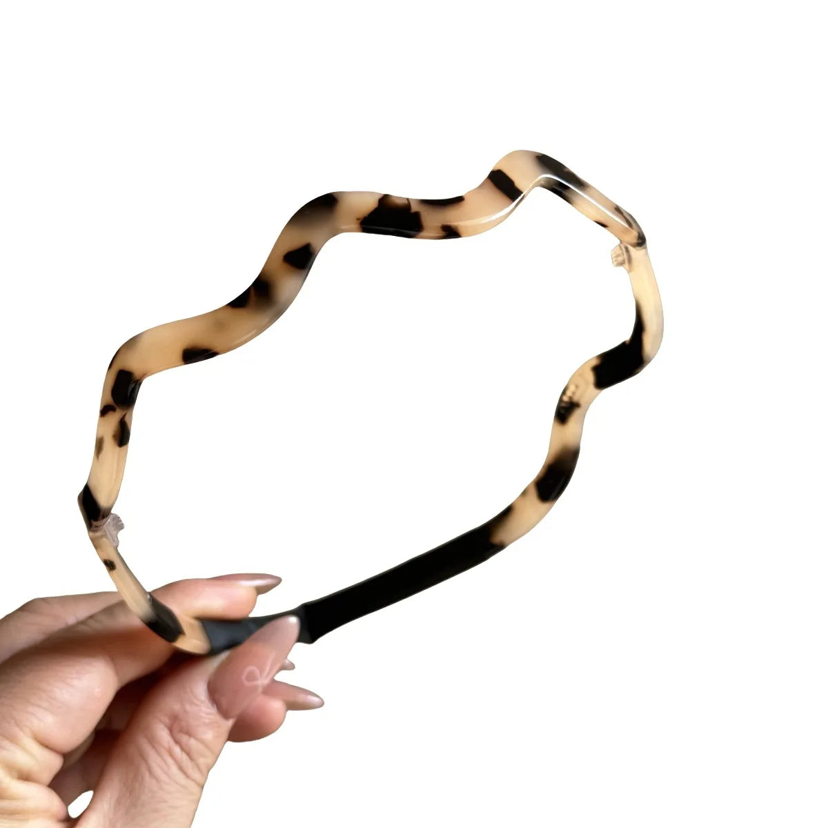 Una mano sostiene unos aretes de pelo ondulado de acetato color caparazón de tortuga.