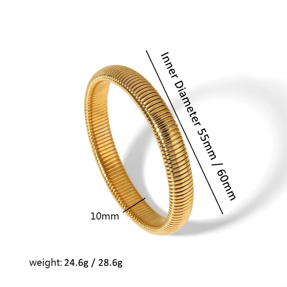 A close-up view of a gold-toned elastic bangle bracelet with a textured surface and a measurement guide.