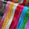 A close-up display of various rainbow glitter hair extensions in vibrant colors like pink, gold, silver, red, blue, and green