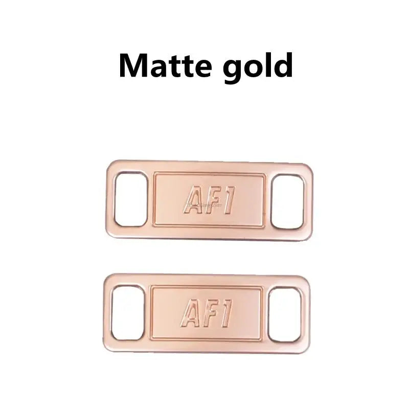 A pair of matte gold diamond shoe charms and laces.