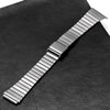 Silberne Edelstahlarmbanduhr mit Gliederkette diagonal auf schwarzem Leder