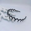 A close-up of black anti-slip toothed hair accessories arranged on a white background.