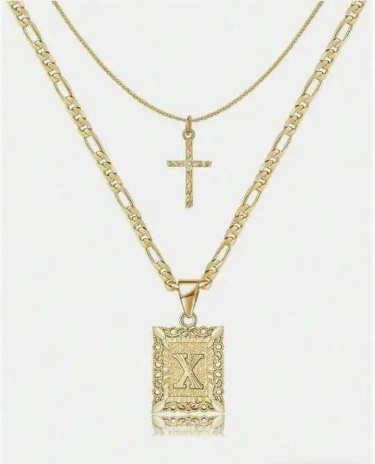 Collier pendentif lettre X et croix dorés sur fond blanc