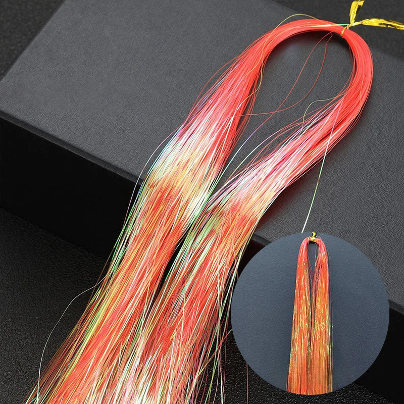 A bundle of rainbow glitter hair extensions with red, orange, and pink strands shown against a dark background.