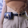 A woman wearing a tan top and light trousers with a black PU leather belt bag and buckle.
