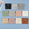 A collection of ten elegant PU leather jewelry pouches in various neutral and blush tones arranged in a row.