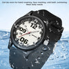 A black watch with a silver dial and silicone strap is shown being splashed by water.