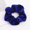 A close-up photo of a royal blue velvet scrunchie with gathered fabric texture.