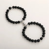 A pair of black natural stone heart couple bracelets with silver accents.