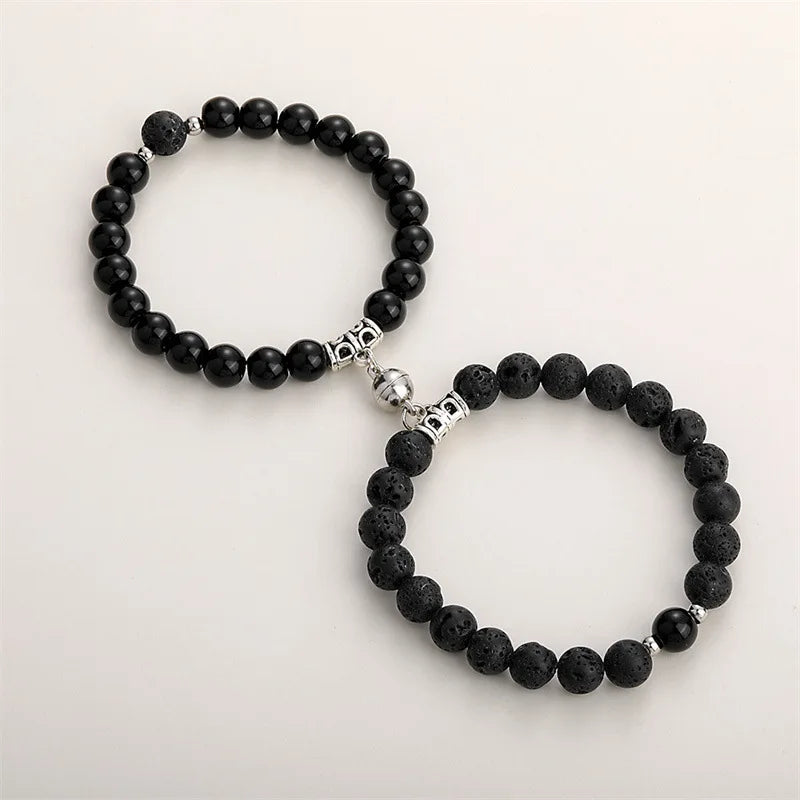 A pair of black natural stone heart couple bracelets with silver accents.