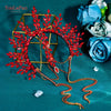 A vibrant red rhinestone floral crown headband displayed on a gold geometric frame against a teal background.