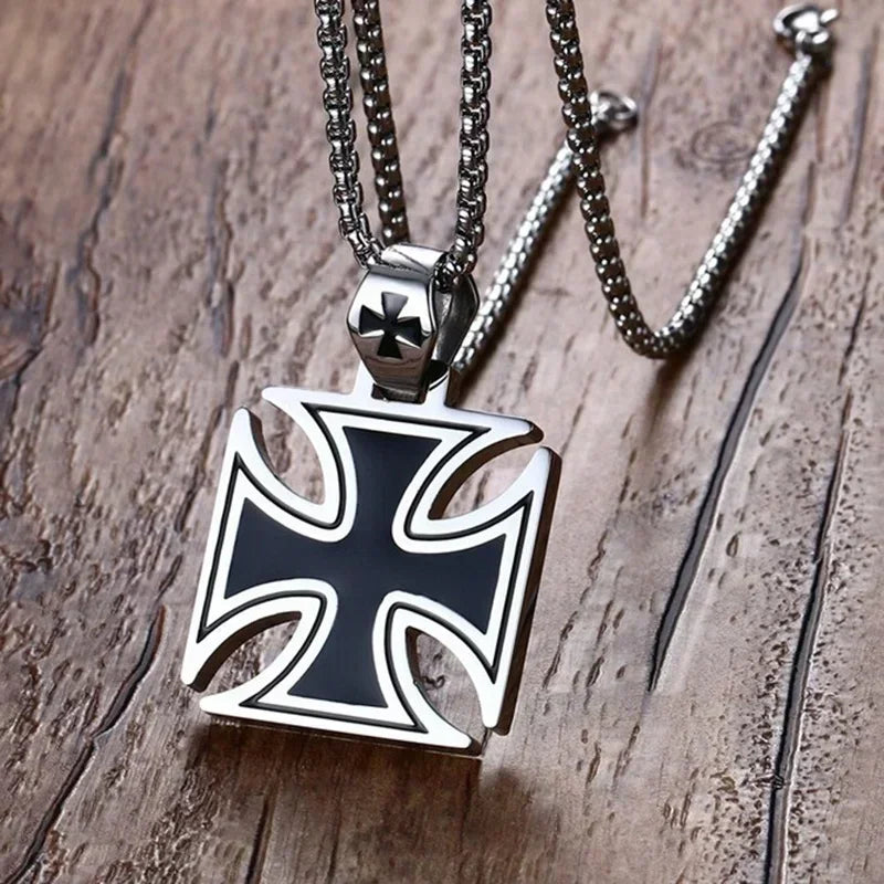 Silver pendant necklace featuring a black cross design on a chain, resting on a wooden surface.