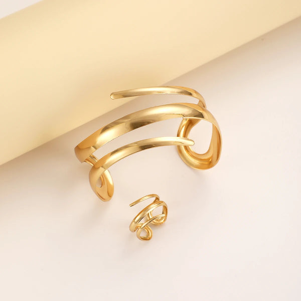 A set of gold geometric bracelets and rings displayed on a light background.