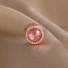 Rose gold charm pendant featuring a pink gemstone surrounded by small clear diamonds.