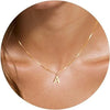 A gold plated alphabet initial necklace worn around the neck against skin.