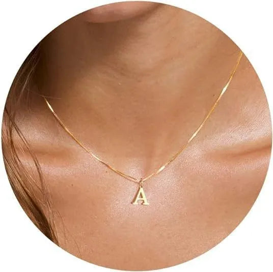 A gold plated alphabet initial necklace worn around the neck against skin.
