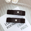 A close-up of a dark brown buckle-free elastic casual belt with a silver-toned buckle resting on a white card.