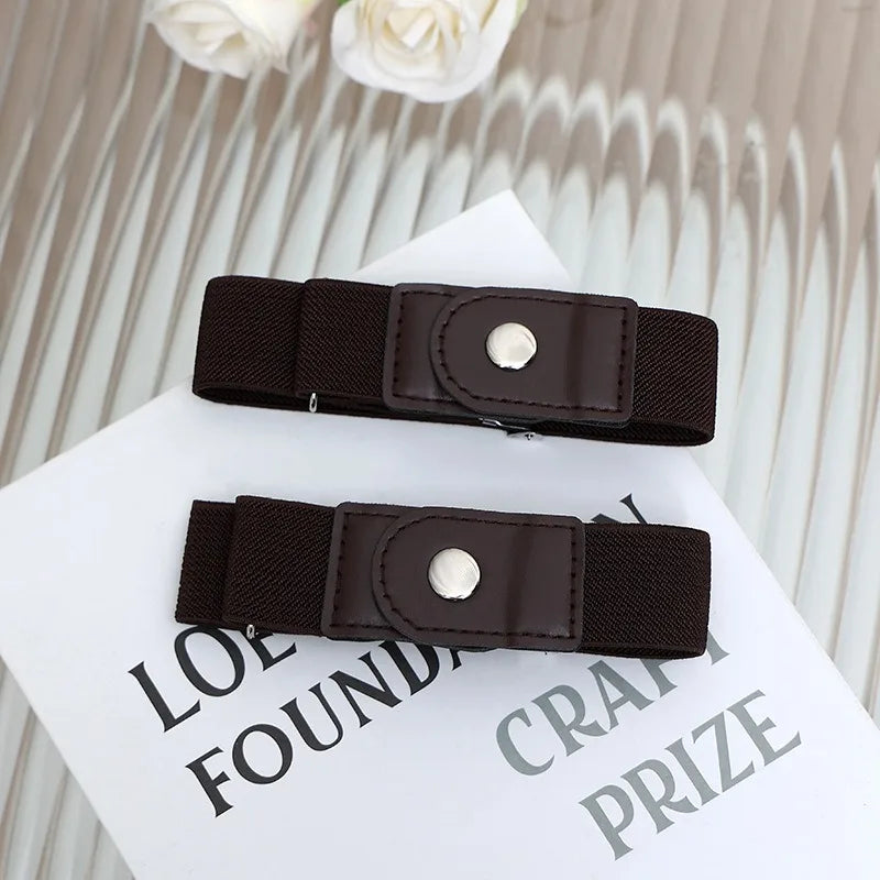A close-up of a dark brown buckle-free elastic casual belt with a silver-toned buckle resting on a white card.