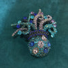 Broche florale en cristal élégante avec des pierres de couleur violette et bleue.