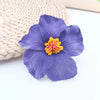 A single purple flower with a yellow center rests on a woven natural fiber background.