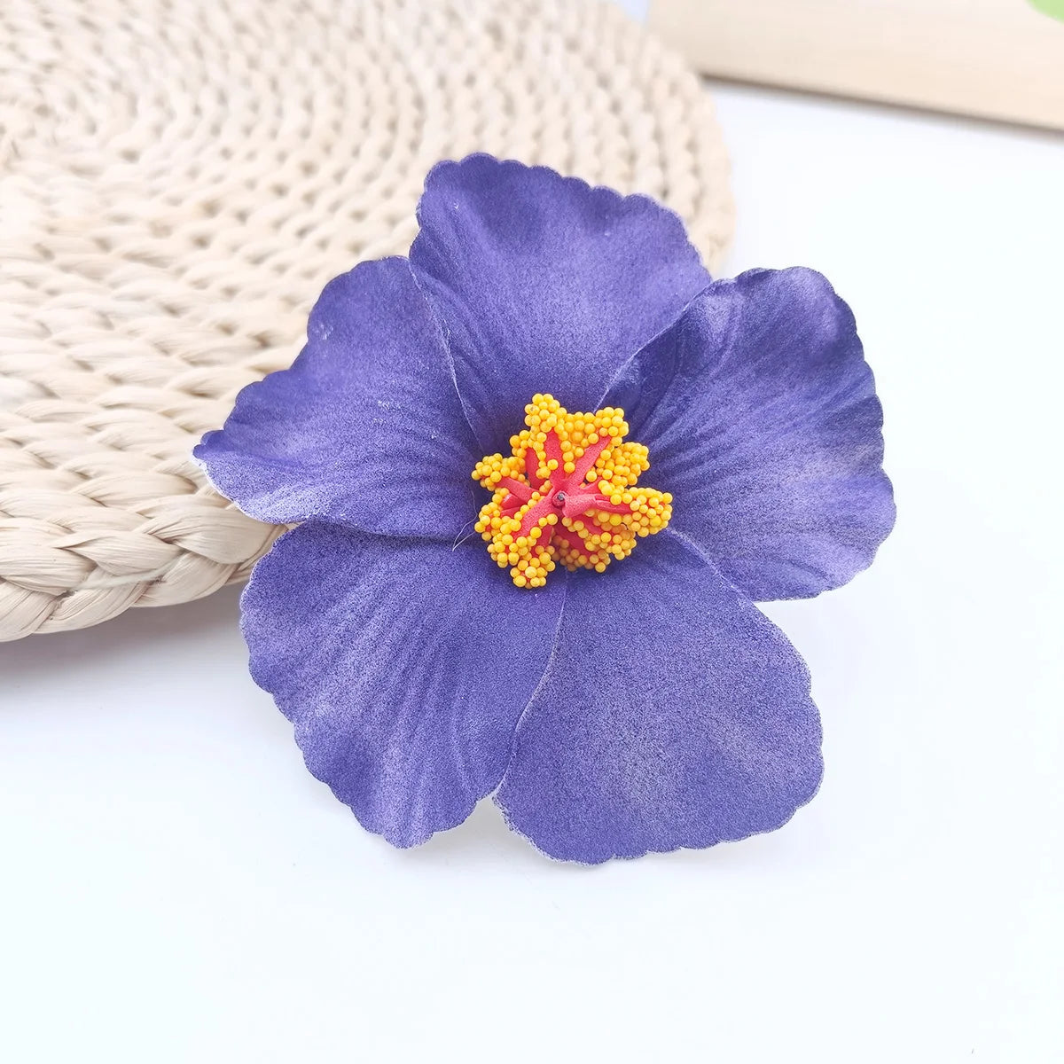 A single purple flower with a yellow center rests on a woven natural fiber background.