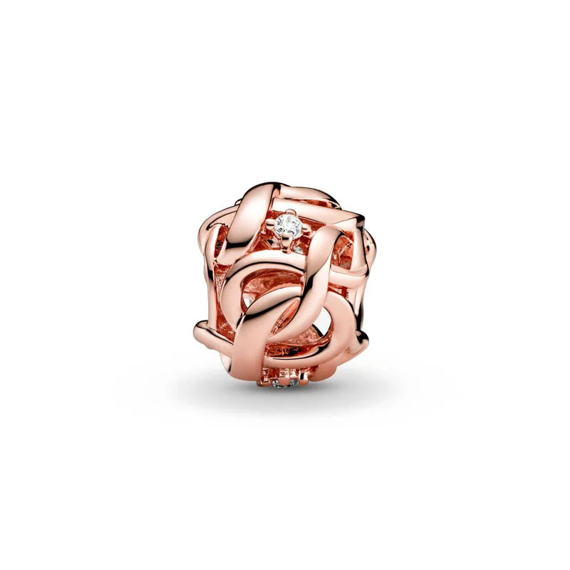 A close-up of a rose gold ring featuring an intertwined design and a clear diamond setting.