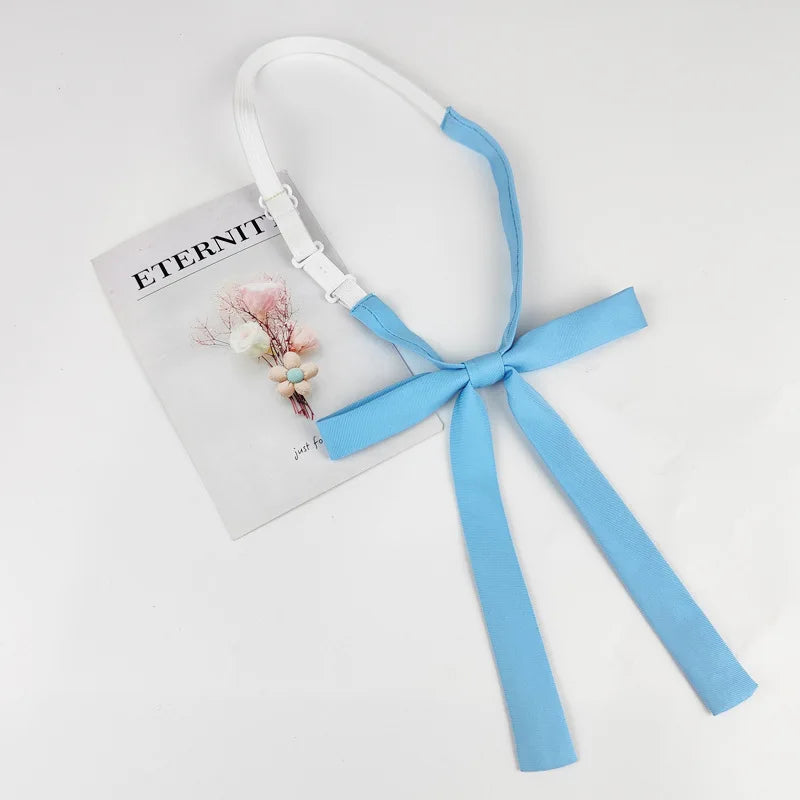 A white and blue ribbon tie set featuring a butterfly bow and long streamers, displayed next to a piece of paper.