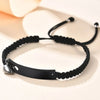 Schwarzes Perlenarmband mit silbernem Anhänger auf weißer Oberfläche.