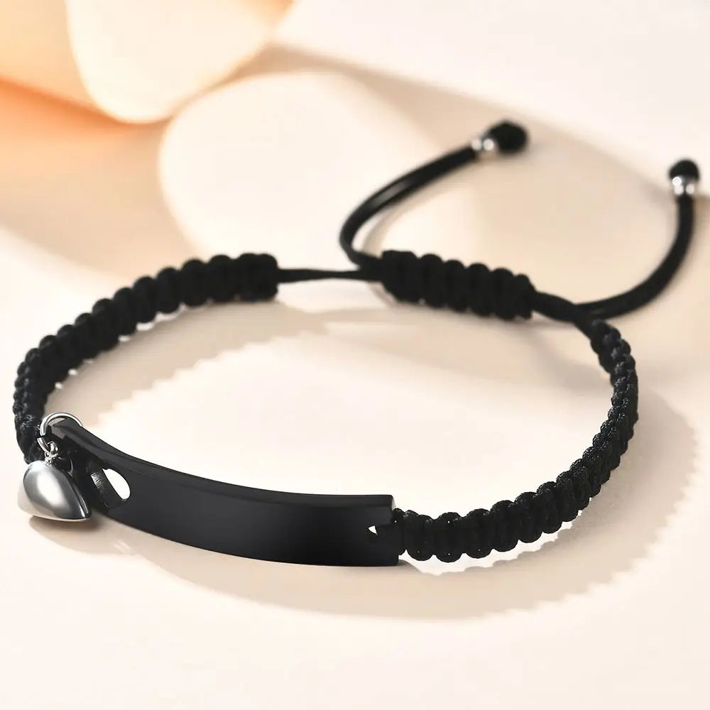 Schwarzes Perlenarmband mit silbernem Anhänger auf weißer Oberfläche.