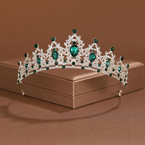 An elegant crystal baroque bridal tiara headpiece with green gemstones resting on a brown box.