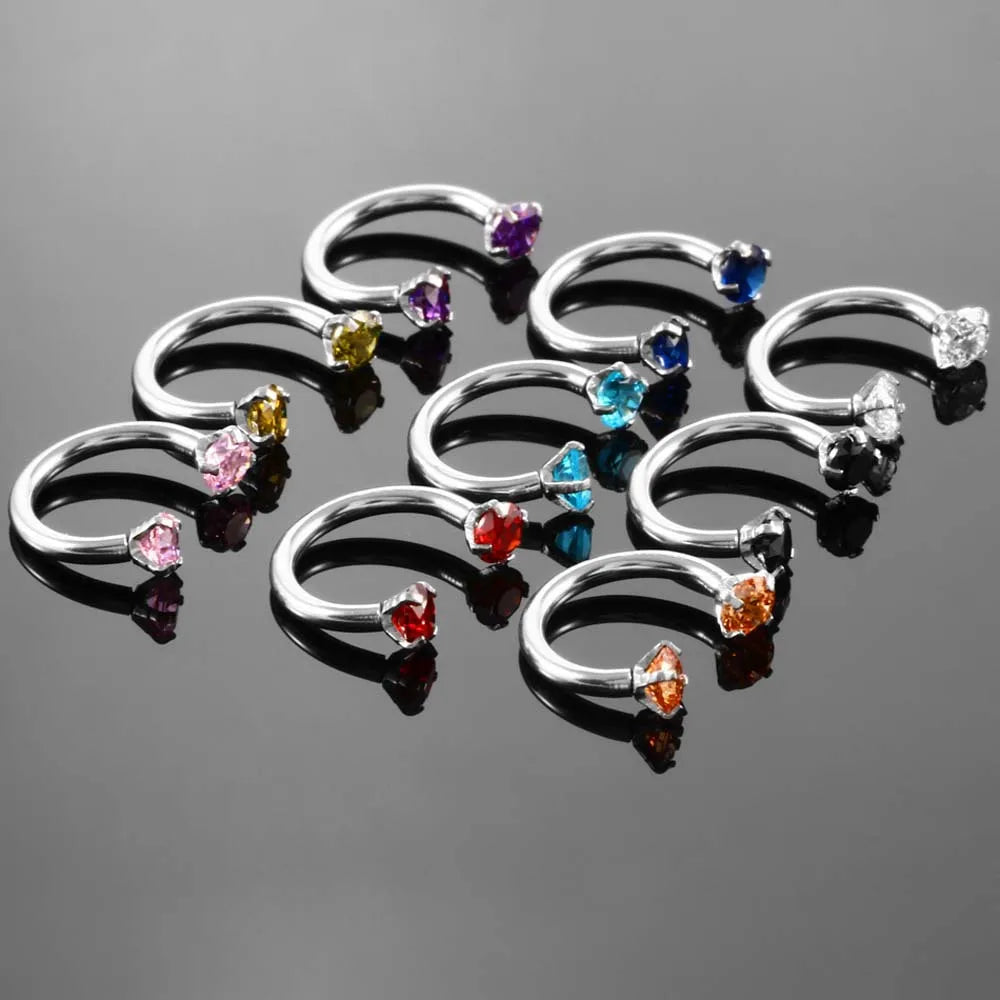 A collection of stainless steel crystal hoop ear piercings in various colors including purple, yellow, blue, and clear.
