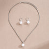 A delicate silver pearl jewelry set featuring matching dangle earrings and a pendant necklace.