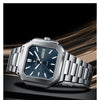 A silver stainless steel quartz watch with a dark blue dial and a metal bracelet is displayed on a dark surface.