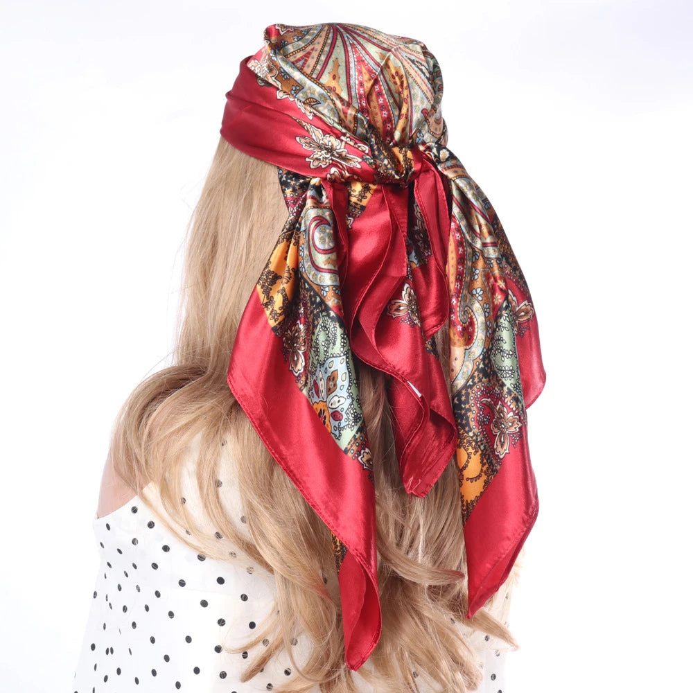 Blondes Haar ist mit einem roten, gemusterten Boho-Seidenschal als Kopftuch gebunden.