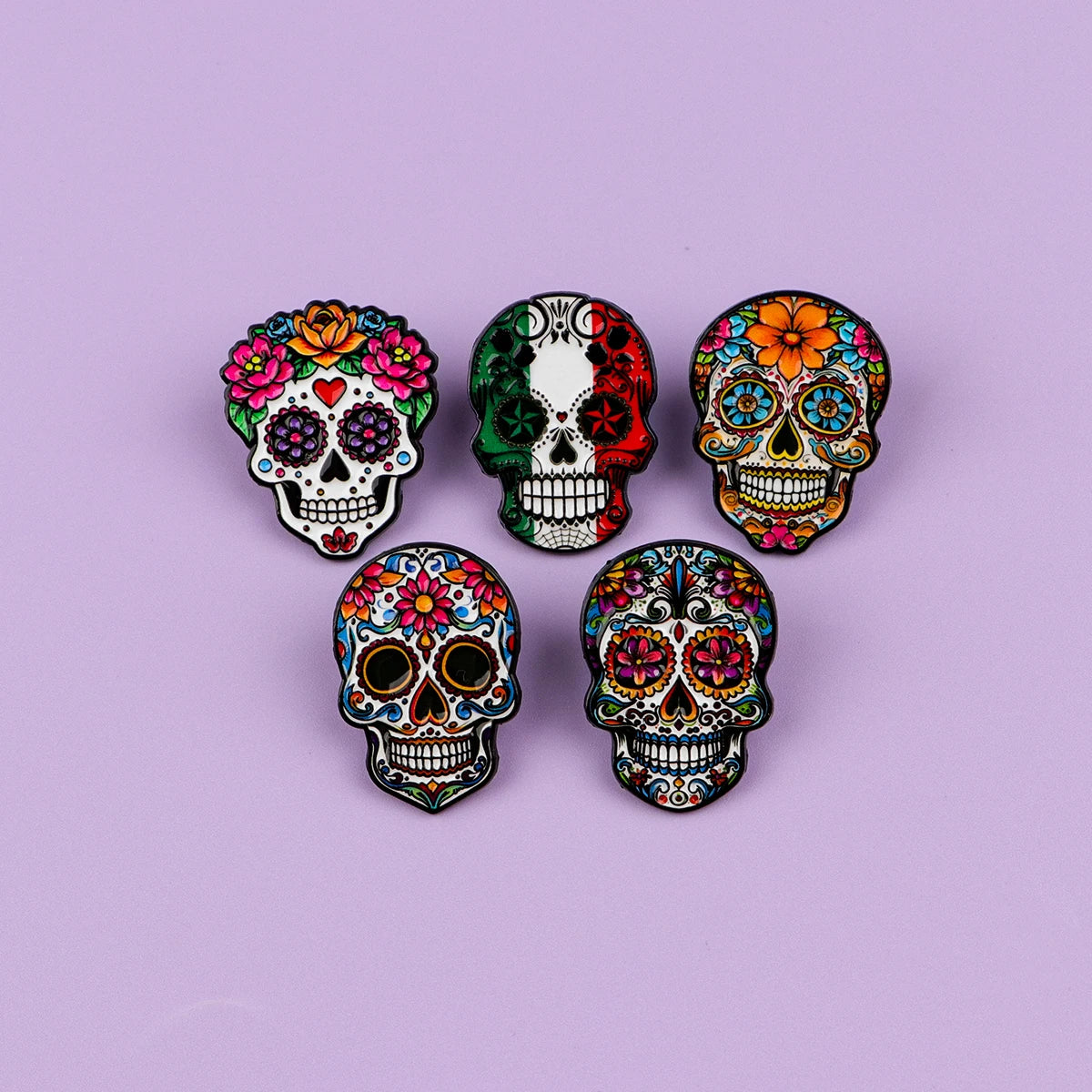 A collection of seven colorful Mexican skull enamel pins featuring vibrant floral and decorative designs.