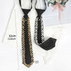 Black neck tie adorned with gold and silver rhinestones and pearls displayed on a white fur background.