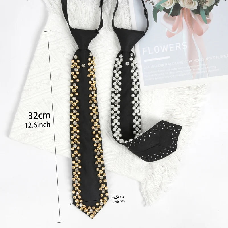Black neck tie adorned with gold and silver rhinestones and pearls displayed on a white fur background.