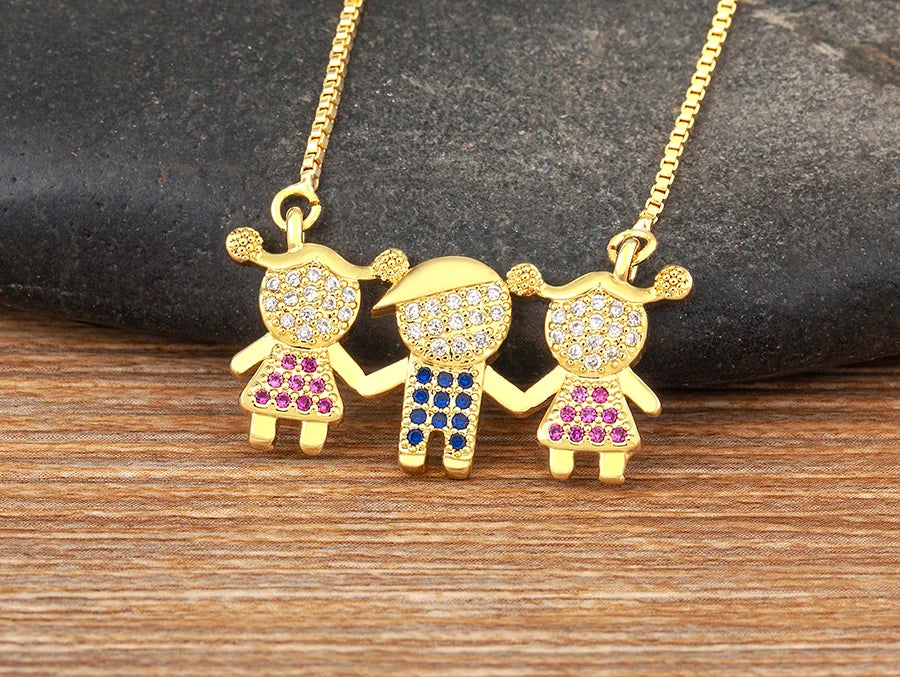 Collier délicat de couleur or avec trois pendentifs en forme d'enfants, ornés de pierres CZ de différentes couleurs.