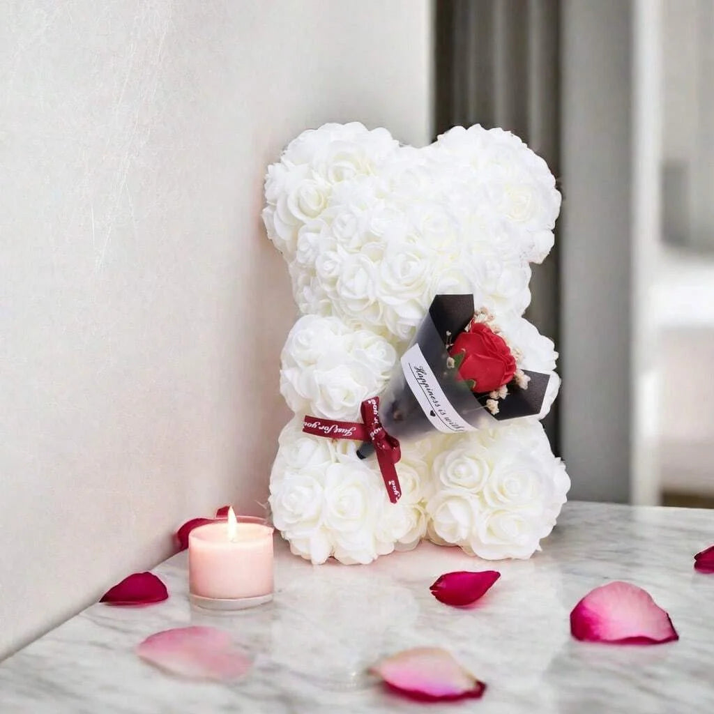 Bouquet de ours en peluche rose et blanc avec des pétales de roses roses sur une surface de marbre.
