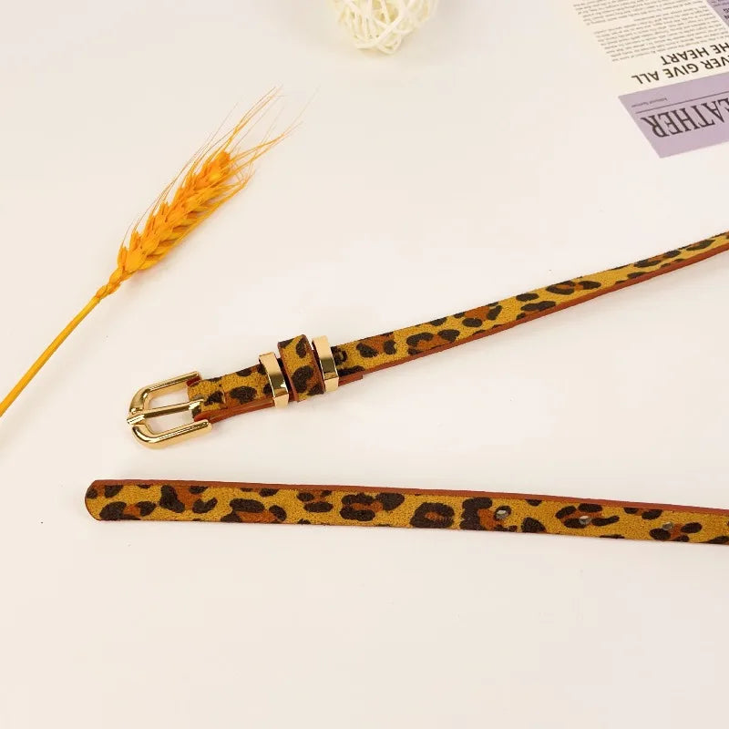 A slim leopard print leather belt with a vintage gold-toned buckle displayed on a white background.