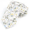 Une pile de nœuds papillons en coton à motifs floraux élégants, avec des fleurs jaunes et bleues sur fond blanc.