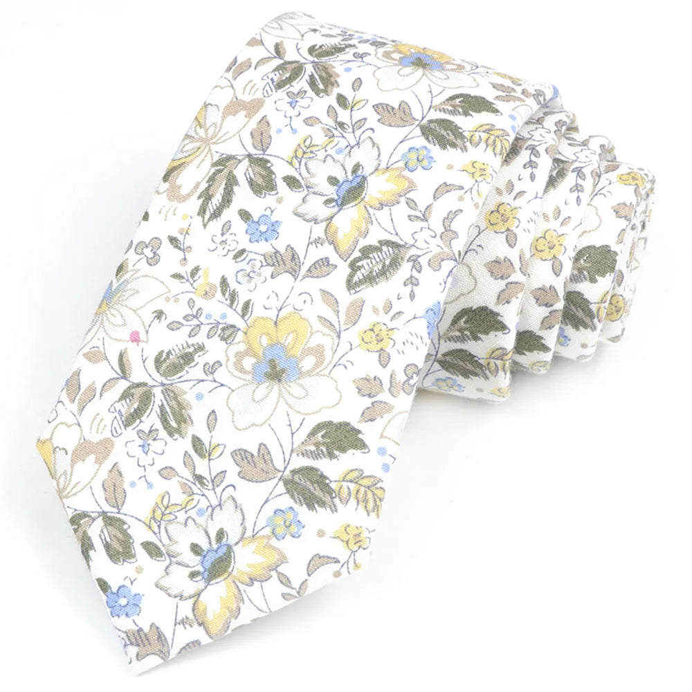 Une pile de nœuds papillons en coton à motifs floraux élégants, avec des fleurs jaunes et bleues sur fond blanc.