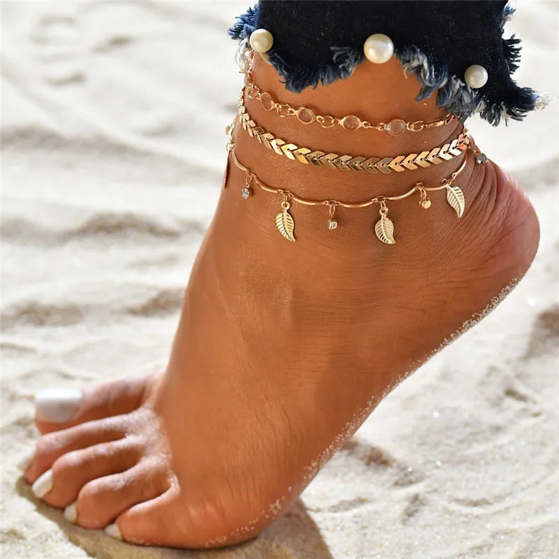 A close-up of a foot adorned with multiple gold and pearl anklet bracelets