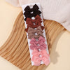 A display of nine handmade ribbon bow hair clips in various shades of brown, pink, and black arranged on a wooden board.